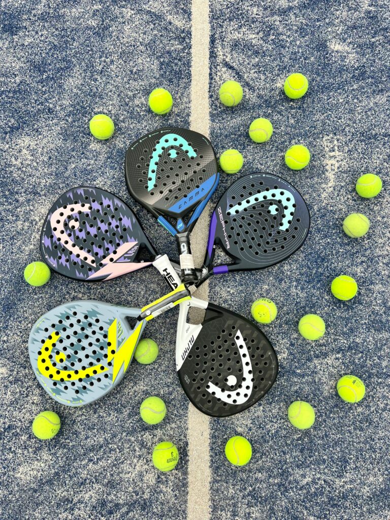 Plusieurs quattes de padel formant un cercle accompagnées de balles de padel sur gazon synthétique bleu